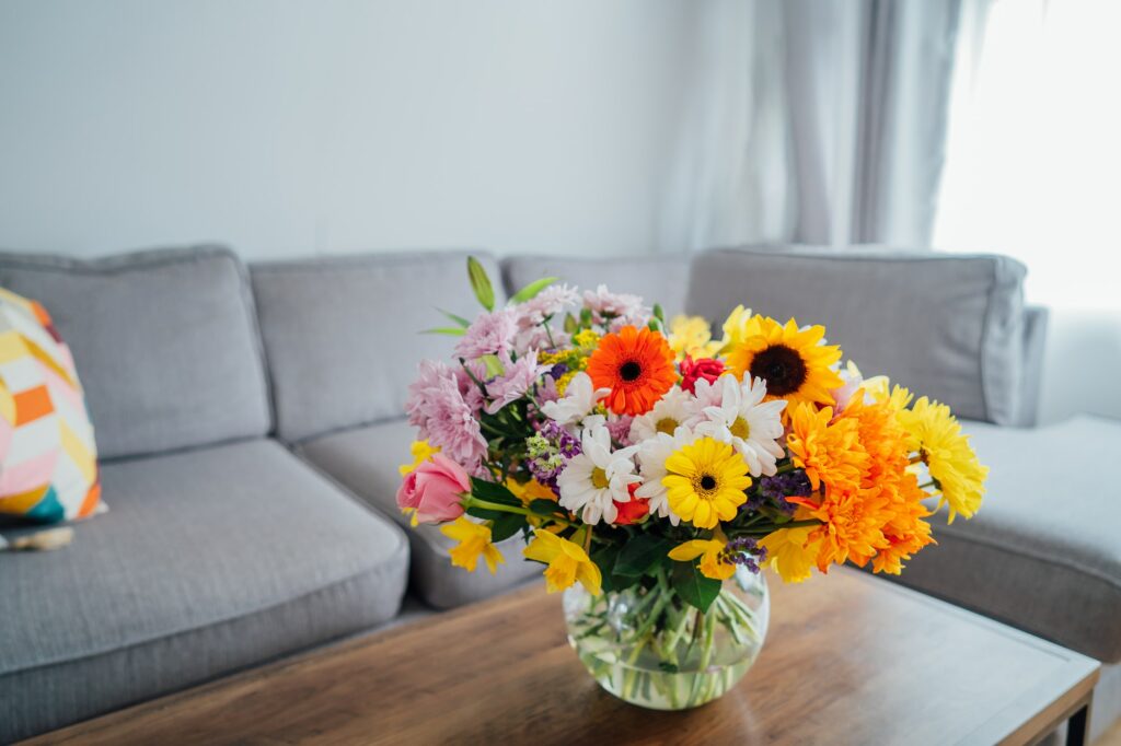 Vase with huge multicolor various flower bouquet on the coffee table